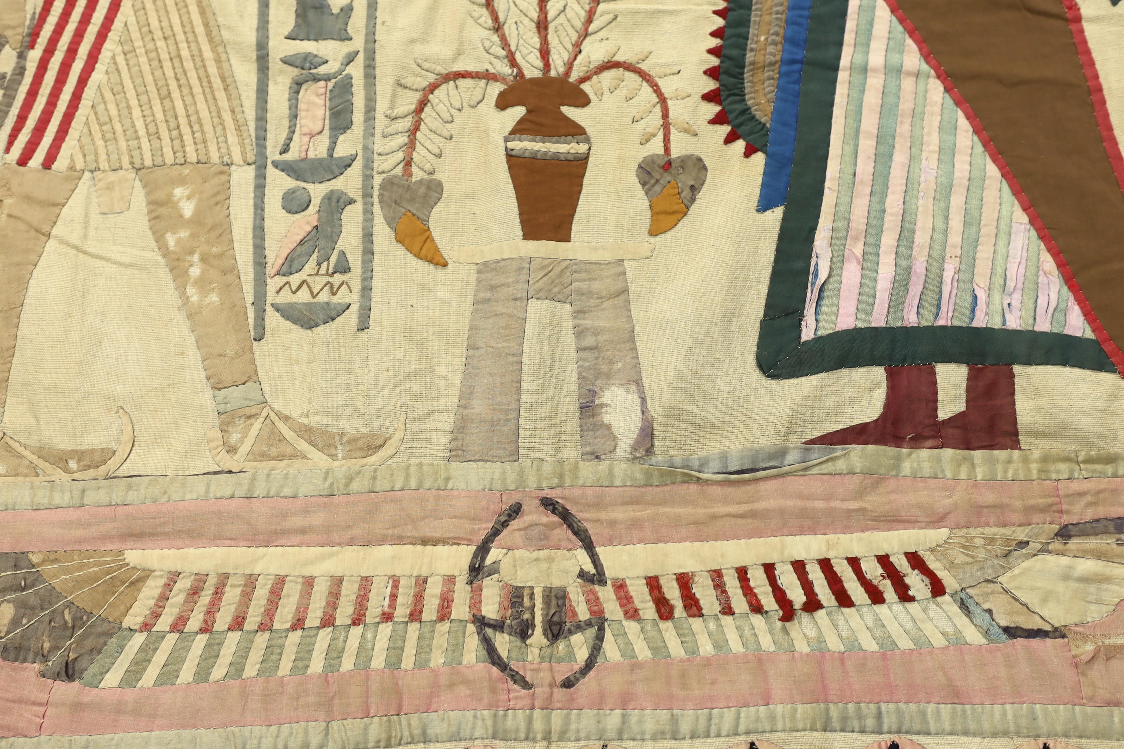 A 1930’s large Egyptian appliqué wall hanging, depicting Wadjet, (Goddess and protector of Kings) and Amun (God of wind) surrounded by hieroglyphic decorative symbols, 134cm wide x 268cm long